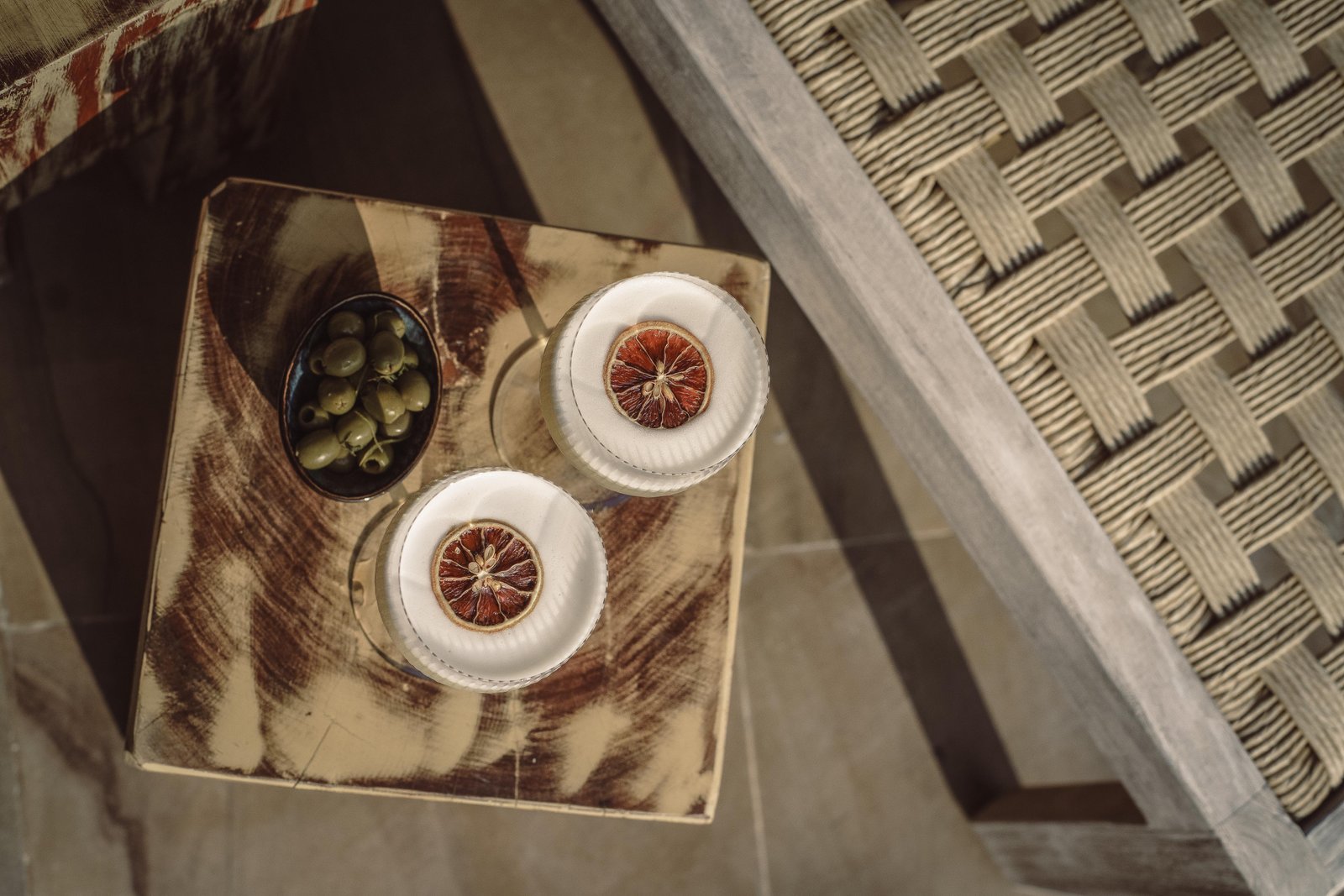 Two cocktails on a poolside tray — arriving and staying, nowhere else to be